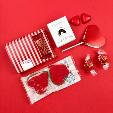 Assorted Valentine's Day treats including heart-shaped cookies, candy, and a box of chocolates on a red background.