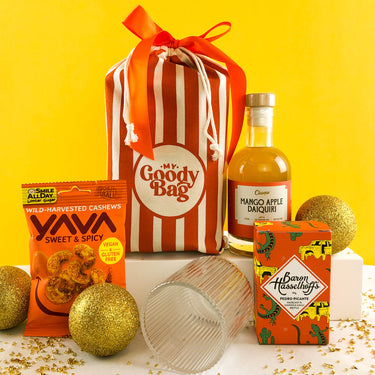 Daquiri, brittle from Baron Hasselhoff and Sweet & Spicy cashews flank a ornage striped Goody Bag alongside a beautiful reeded glass by My Goody Bag