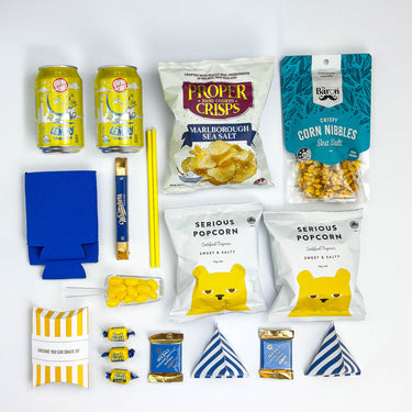 Assorted snacks and drinks including cans, popcorn bags, and chips on a white background