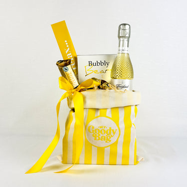 Yellow canvas gift bag filled wtih treats and prosecco