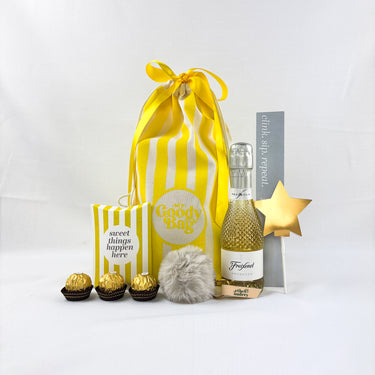 Gift set with a yellow striped bag, small bottle, and decorative items on a white background